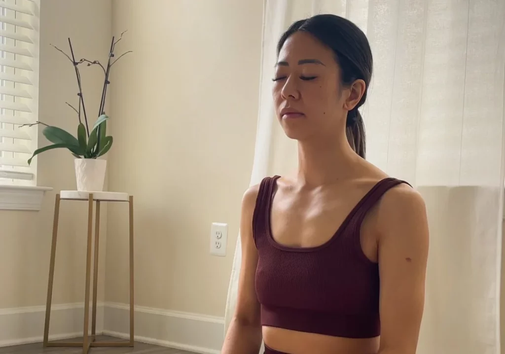 Woman sitting on yoga mat practicing gratitude and meditating